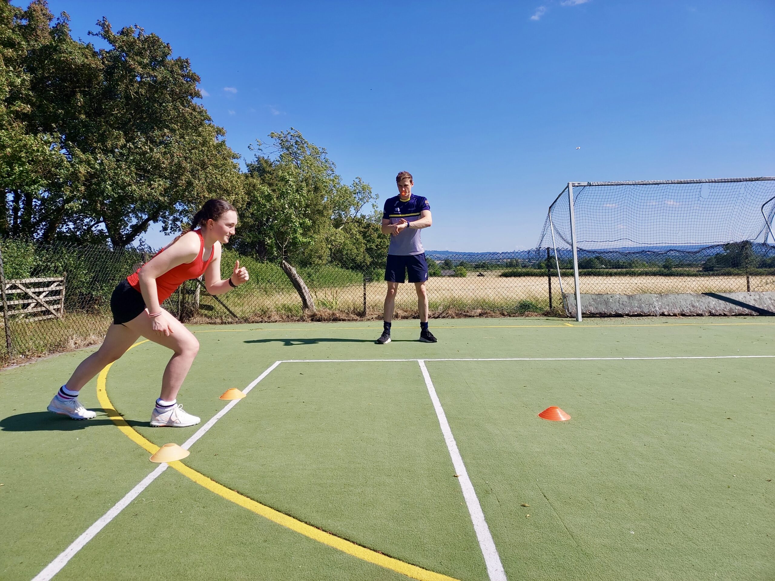 Hockey conditioning drill – sprint timing and coaching Hockey coach preparing to time a sprint as a player gets ready between cones during a physical conditioning session on the sideline