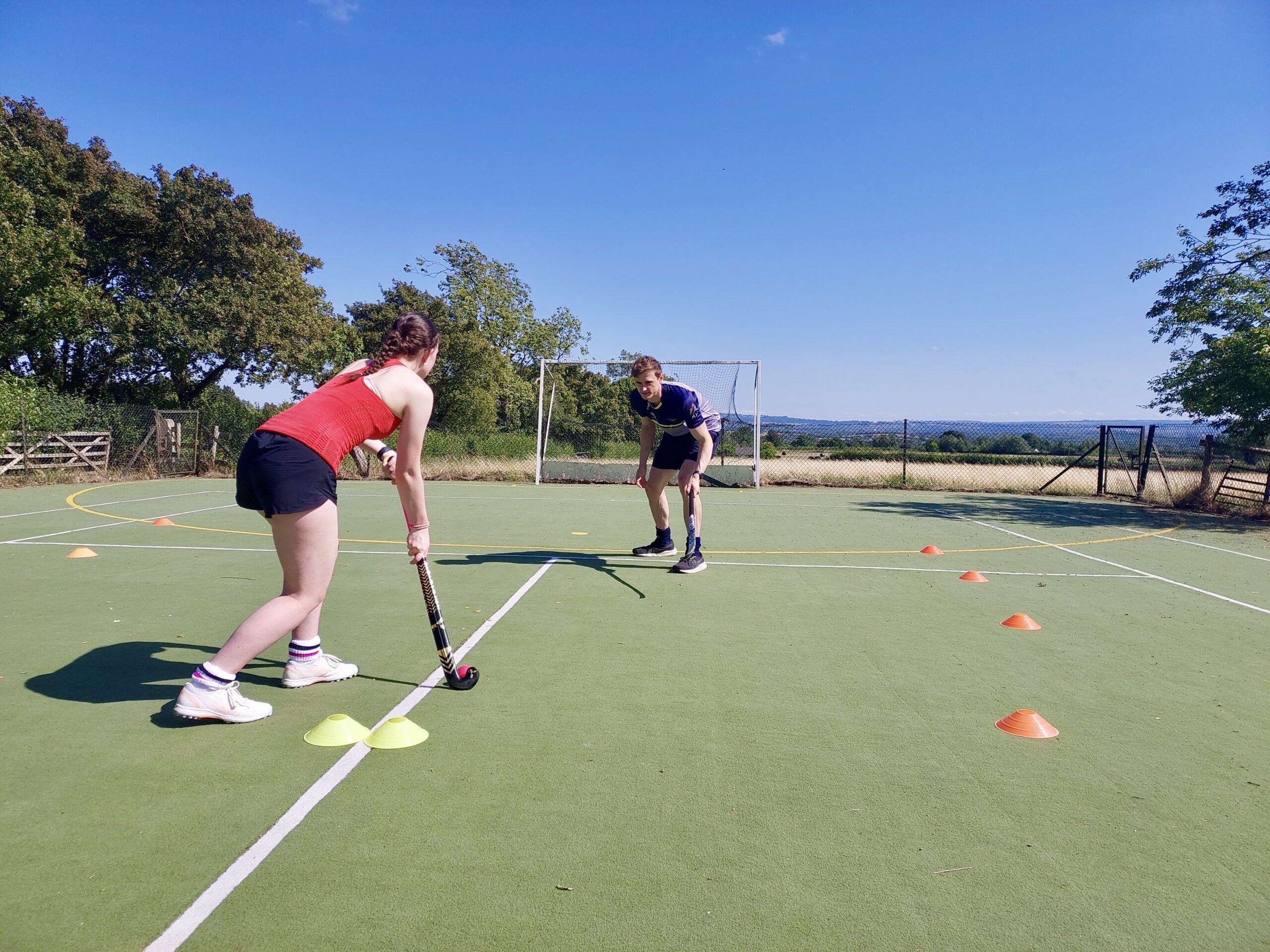 1v1 defensive coaching drill – channeling attacker Hockey coach demonstrating defensive channeling during a 1v1 drill, facing a young attacker positioned at the end of a cone-marked channel